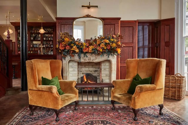 Cozy meeting space in The Hound's Green Room with plush armchairs and fireplace.
