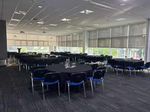 Spacious T&D Café meeting room for workshops, featuring round tables and natural light.