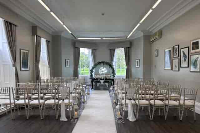 Wedding ceremony setup at Eastwood Hall featuring cross-back chairs and neon focal point.