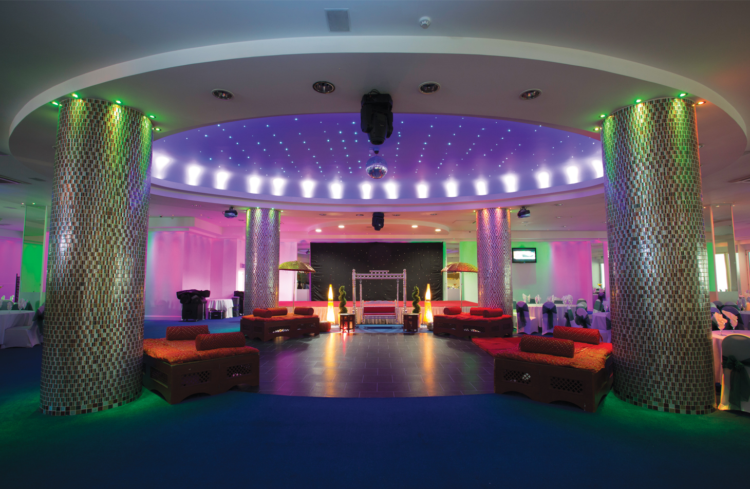 Spacious Banqueting Suite in London with vibrant purple and green lighting, ideal for celebrations.