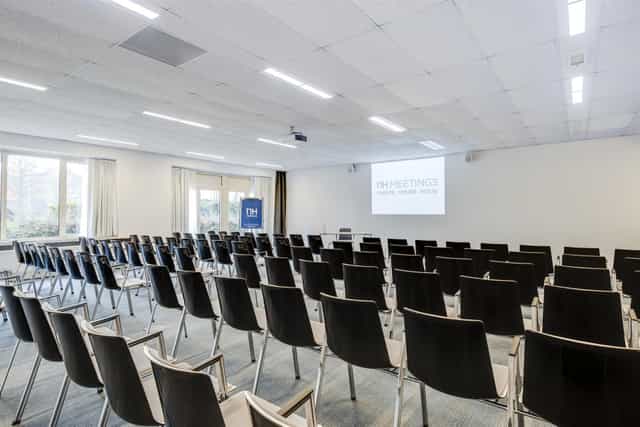 Modern conference room with black chairs for meetings at NH Eindhoven Hotel.