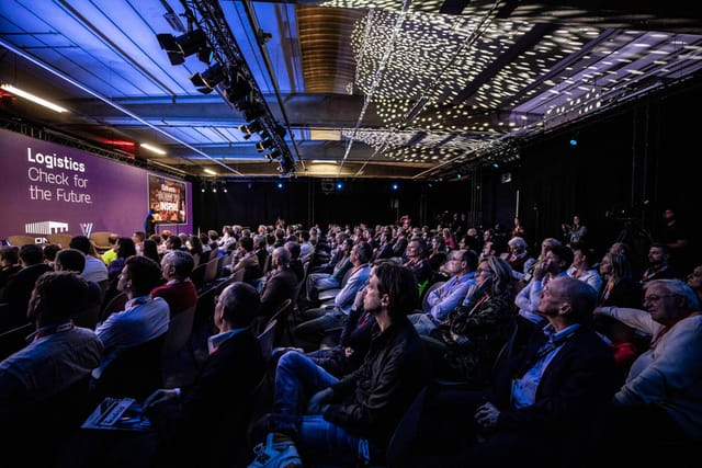 Engaged audience at Avenue Blackbox conference with focused lighting and networking.