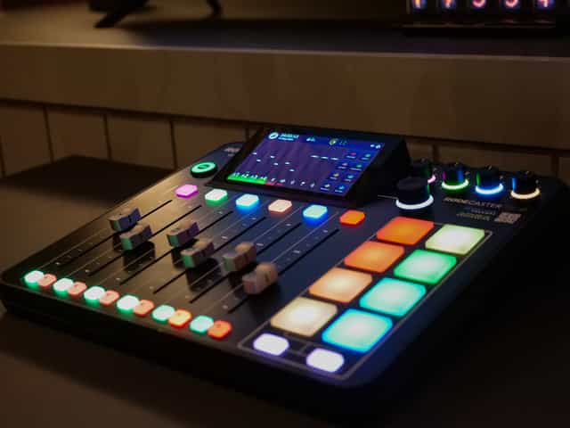 High-tech audio mixer with LED indicators in Colony Jactin House podcast room setup.