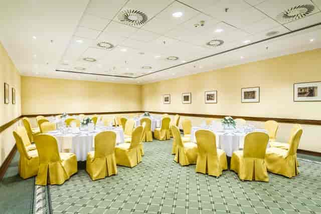 Banquet setup in Arche Hotel Poloneza plenary room with yellow chairs for corporate events.