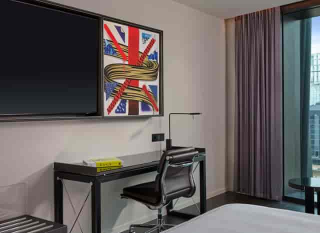 Modern hotel room with desk and art in art'otel London Hoxton for business travelers.