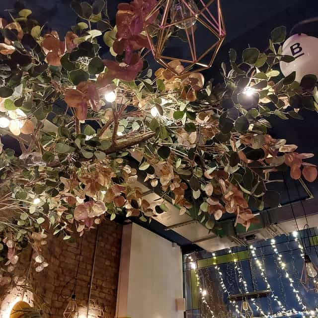 Botanical cocktail bar interior, lush overhead installation