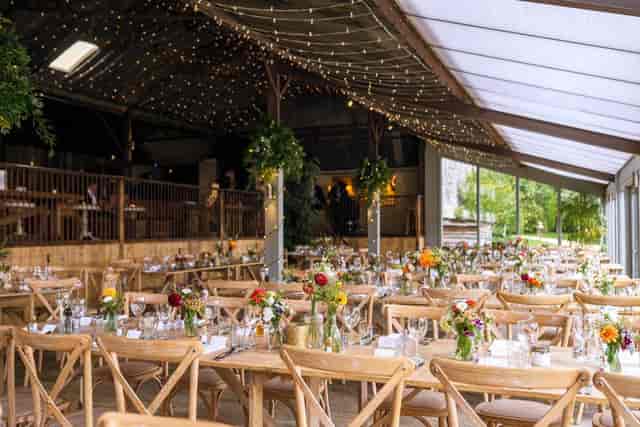 Rustic barn wedding venue with communal tables for upscale banquet events.