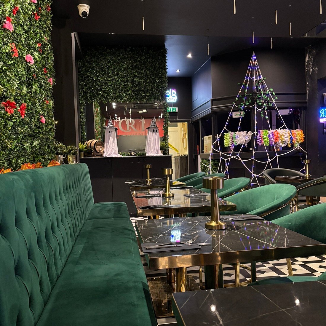 The Leaf Room Halloween decor: emerald green velvet lounge with festive ghost installations.