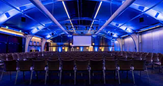 Theater-style keynote setup with blue lighting at 1931 Congrescentrum for corporate events.
