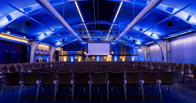 Theater-style keynote setup with blue lighting at 1931 Congrescentrum for corporate events.