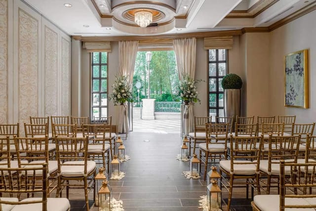 Gold chiavari chairs and floral pedestals in an elegant event space for weddings and corporate galas.