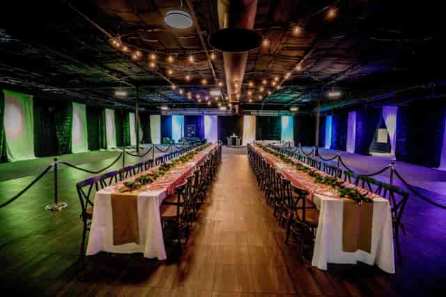Industrial event space with banquet seating, bistro lighting, gala venue, warehouse reception.