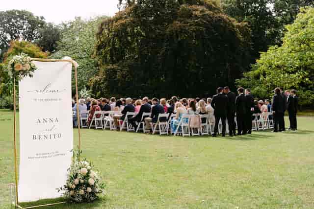 Outdoor ceremony in Fellows' Garden with white chairs and welcome sign for wedding event venue.