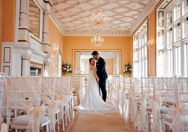 Gold Room wedding ceremony at Holmewood Hall with ornate architecture and elegant Chiavari chairs.