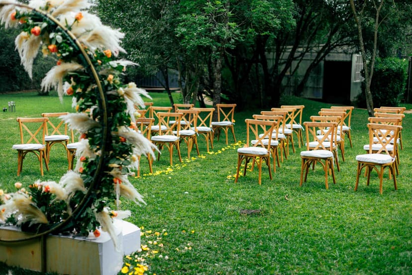 Bohemian crescent floral arch and rustic chairs for an intimate garden wedding ceremony.