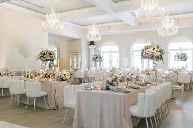 Upscale monochromatic ballroom wedding gala setup with elevated floral centerpieces.