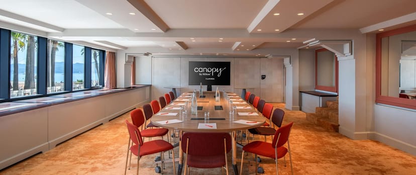 Oval boardroom at Canopy by Hilton Cannes featuring warm decor for corporate meetings and workshops.