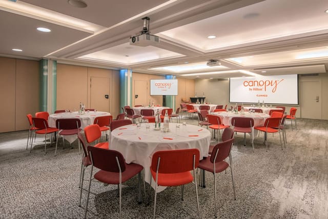 Canopy by Hilton Cannes retreat room with modular banquet setup for corporate workshops and events.