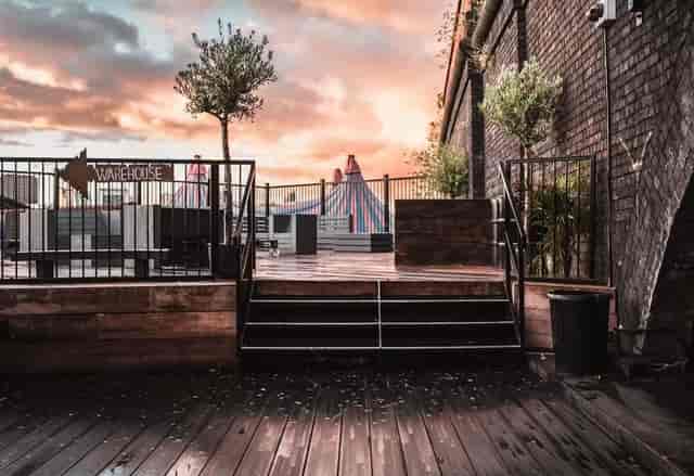 Industrial-chic rooftop terrace with wooden decking for evening reception and corporate event space.