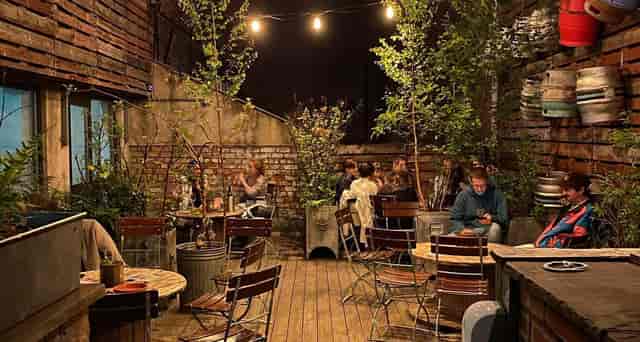 Rooftop Terrace NQ: Cozy industrial outdoor patio with string lights for networking and events.
