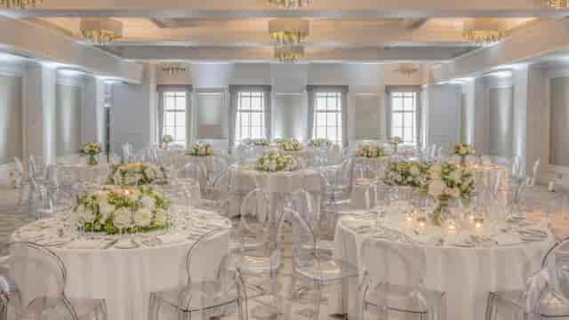 Elegant gala event setup at Water's Edge with ghost chairs and white floral centerpieces.
