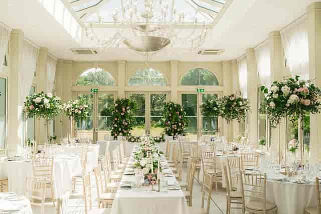 Luxury conservatory wedding reception hall with floral centerpieces for formal events.