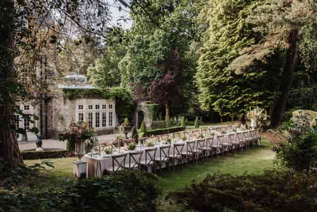 Al fresco wedding reception in lush garden at Wellness & Wilde, long banquet table, scenic dining.
