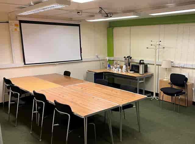 Boardroom-style breakout room at The Lamp House with projector screen for professional meetings.