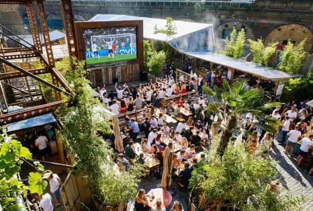 Outdoor sports bar fan zone with communal seating for live events and match day viewing.