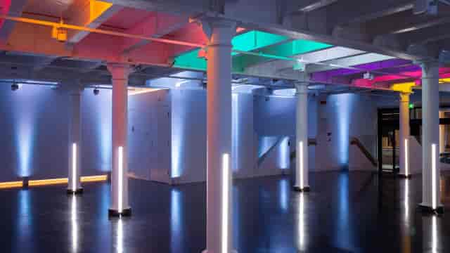 Industrial gallery event space with colored uplighting for brand activations and networking.