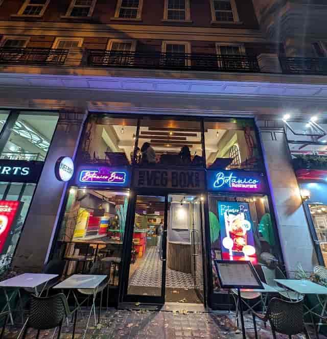 Upstairs event space at The Veg Box Cafe with neon sign, balcony seating for evening gatherings