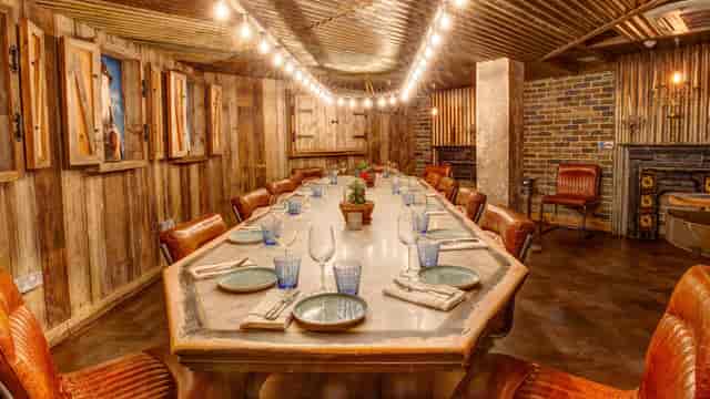 Rustic private dining room with long wooden table, leather chairs, string lights for meetings/events