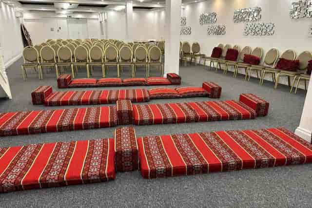 Hybrid event setup at HMS Greenwich with Majlis seating and banquet chairs.