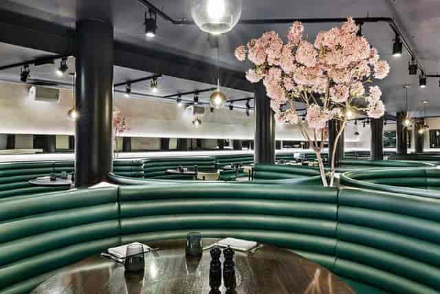 The Astrea venue at Hotel Riu Plaza London with curved emerald booths for private event dining.