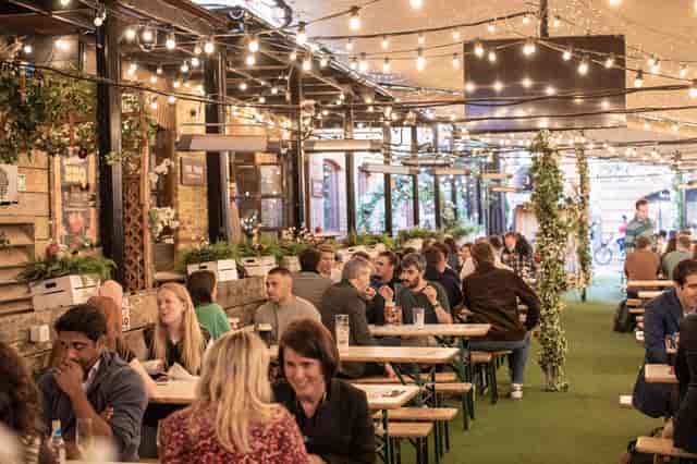 Outdoor venue with festoon lighting and bench seating for networking events in Bermondsey.