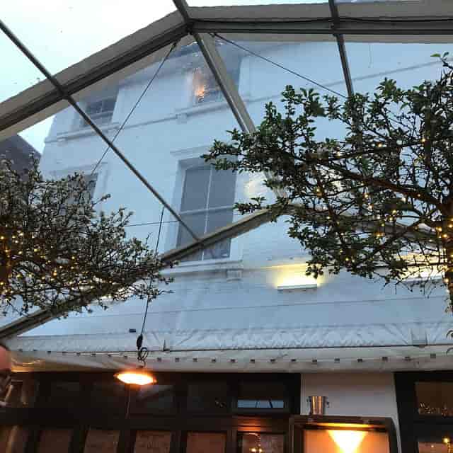 Clear-span marquee venue with string-lit trees for evening wedding and corporate event receptions.