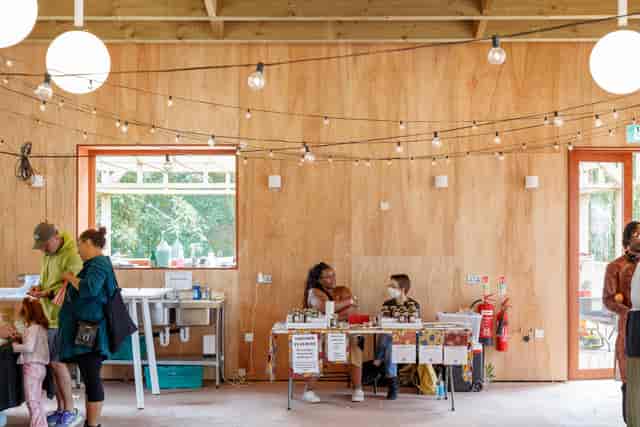 Rustic pop-up classroom with plywood walls and string lights for event registration or vendor space.