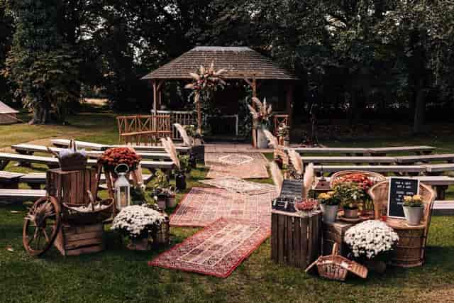 Bohemian outdoor wedding ceremony with rustic wooden crates and vintage rug aisle in Olden Garden.