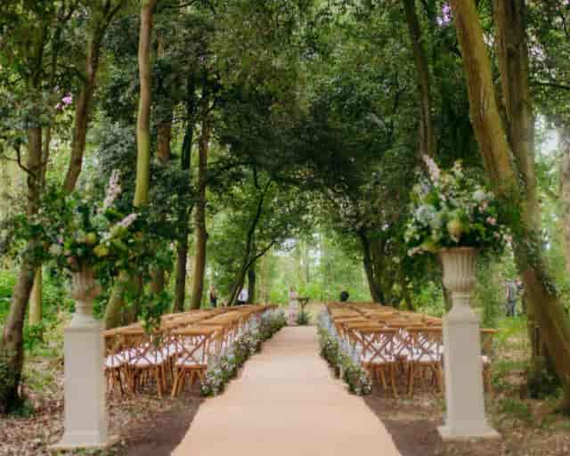 Outdoor garden wedding ceremony in a woodland setting with high-end decor.
