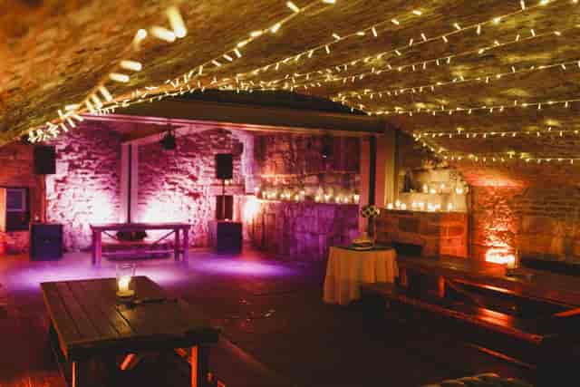 Industrial-chic cellar event space at The Rowantree with warm stone architecture and up-lighting.