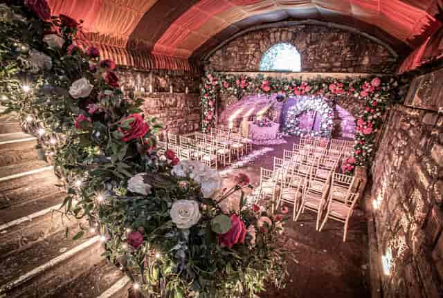 Rustic wedding ceremony in The Caves venue with stone walls and floral decor.
