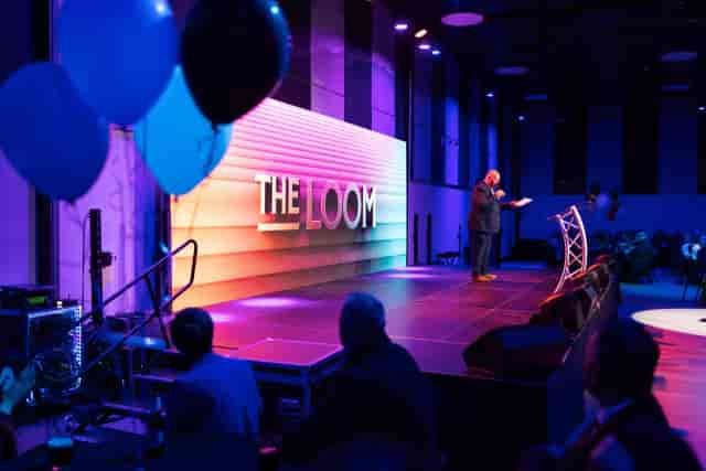 Corporate presentation stage at The Loom Main Hall with dramatic LED branding.