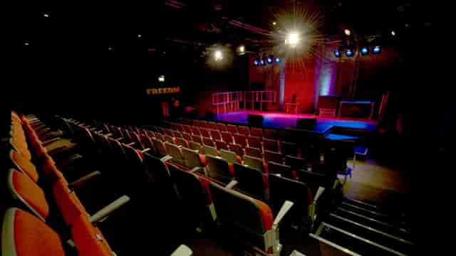 Black-box theatre auditorium with stage lighting for panel discussions and performance events.