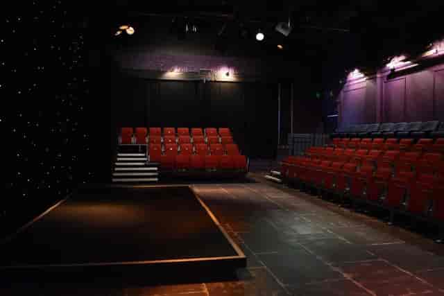 Black-box theater auditorium with tiered seating for event presentations and panel discussions.