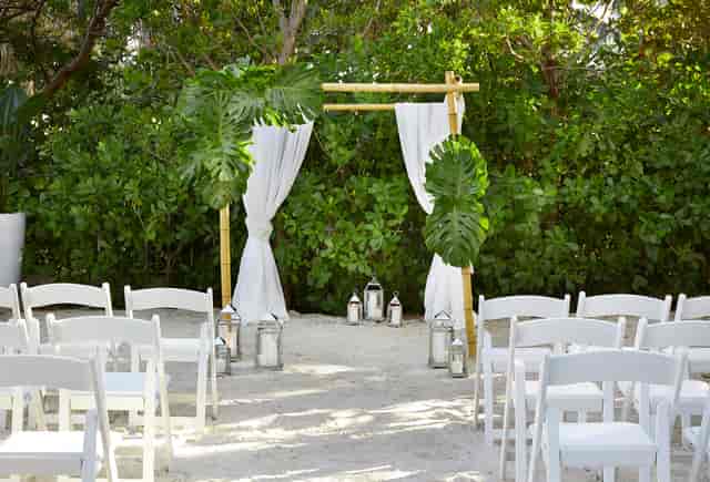 Tropical beach wedding ceremony with bamboo decor and white chairs at Cadillac Hotel & Beach Club.