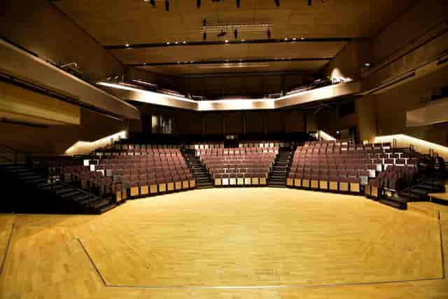 Main Theatre auditorium with thrust stage for corporate keynotes and panel discussions.