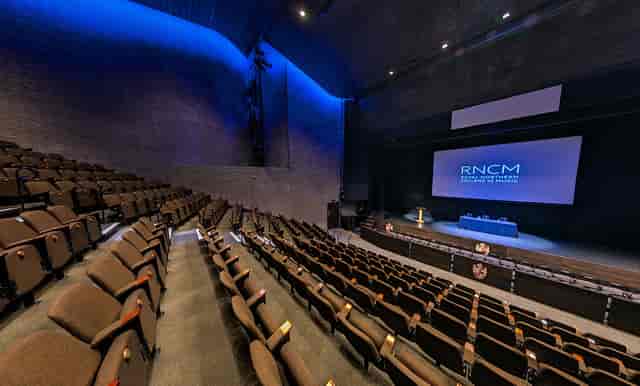 Main Theatre auditorium with blue lighting for corporate presentations and academic conferences.