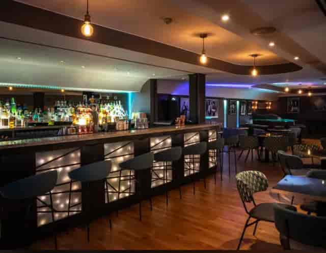 Modern lounge for corporate events and networking at Royal Garden Hotel with lit bar.