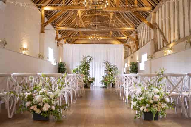 Rustic wedding ceremony in Whole Hall at Allenburys with floral aisle markers and cross-back chairs.