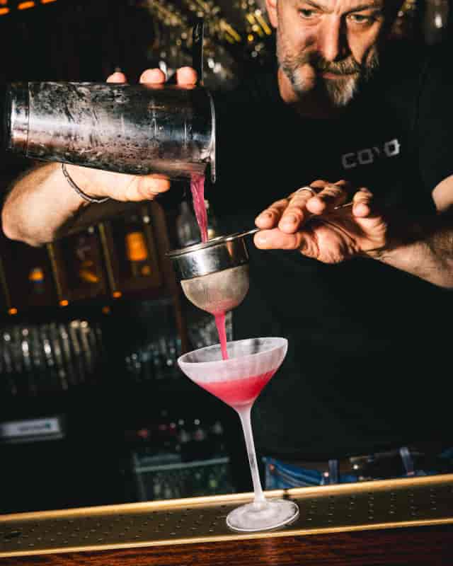 Bartender double-straining cocktail at Bar Coyo for corporate event or evening reception.
